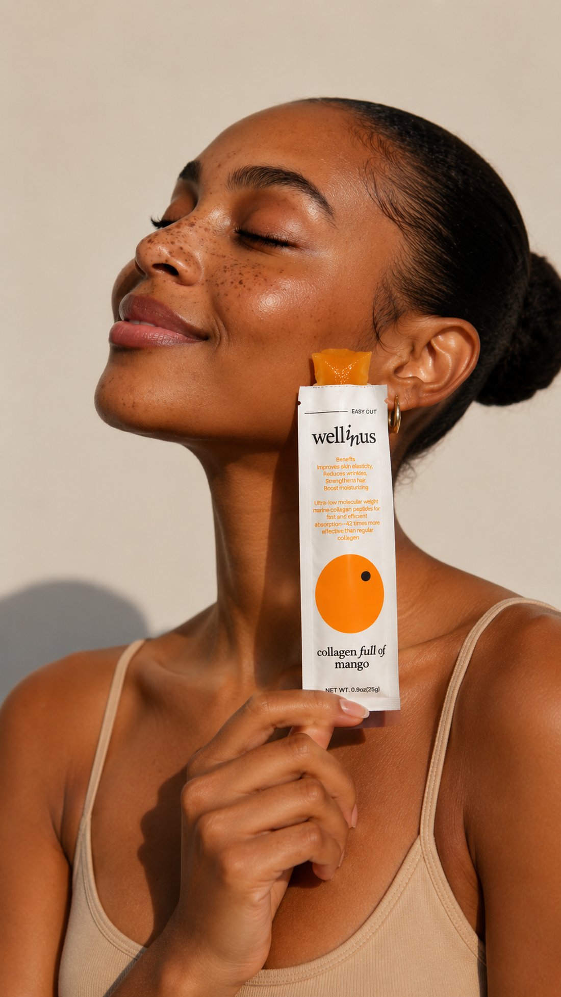 A woman holding a Wellinus mango collagen stick beside her face in warm daylight