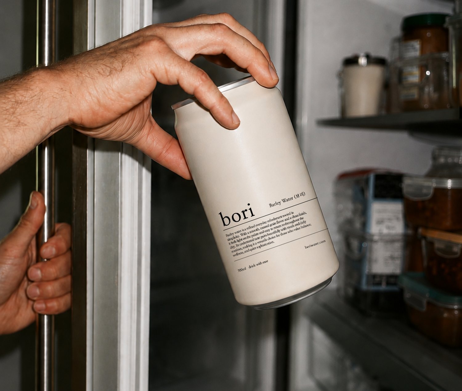 A hand taking a can of Bori barley water from a fridge shelf