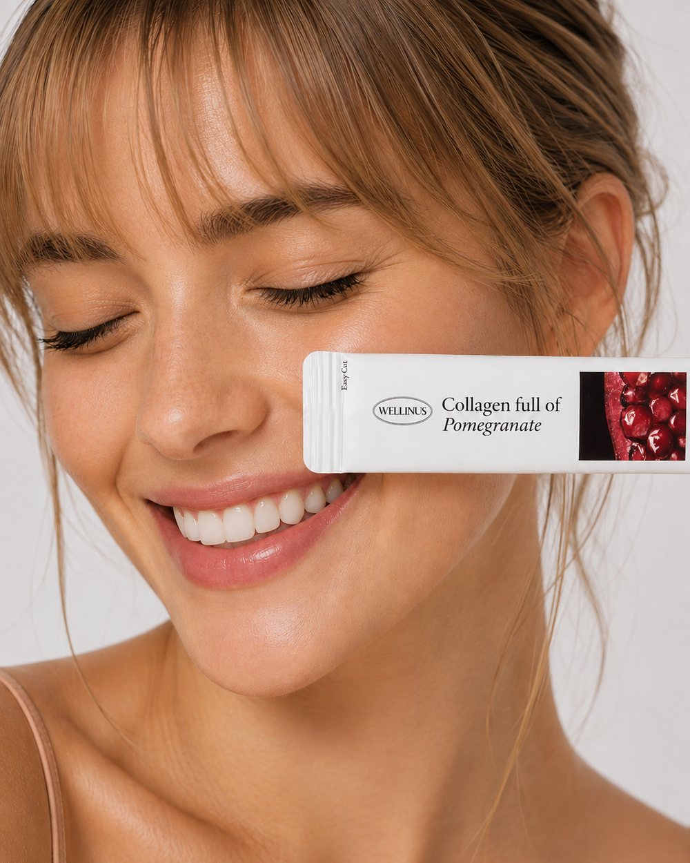 A creator smiling with a Wellinus pomegranate collagen stick held to her cheek